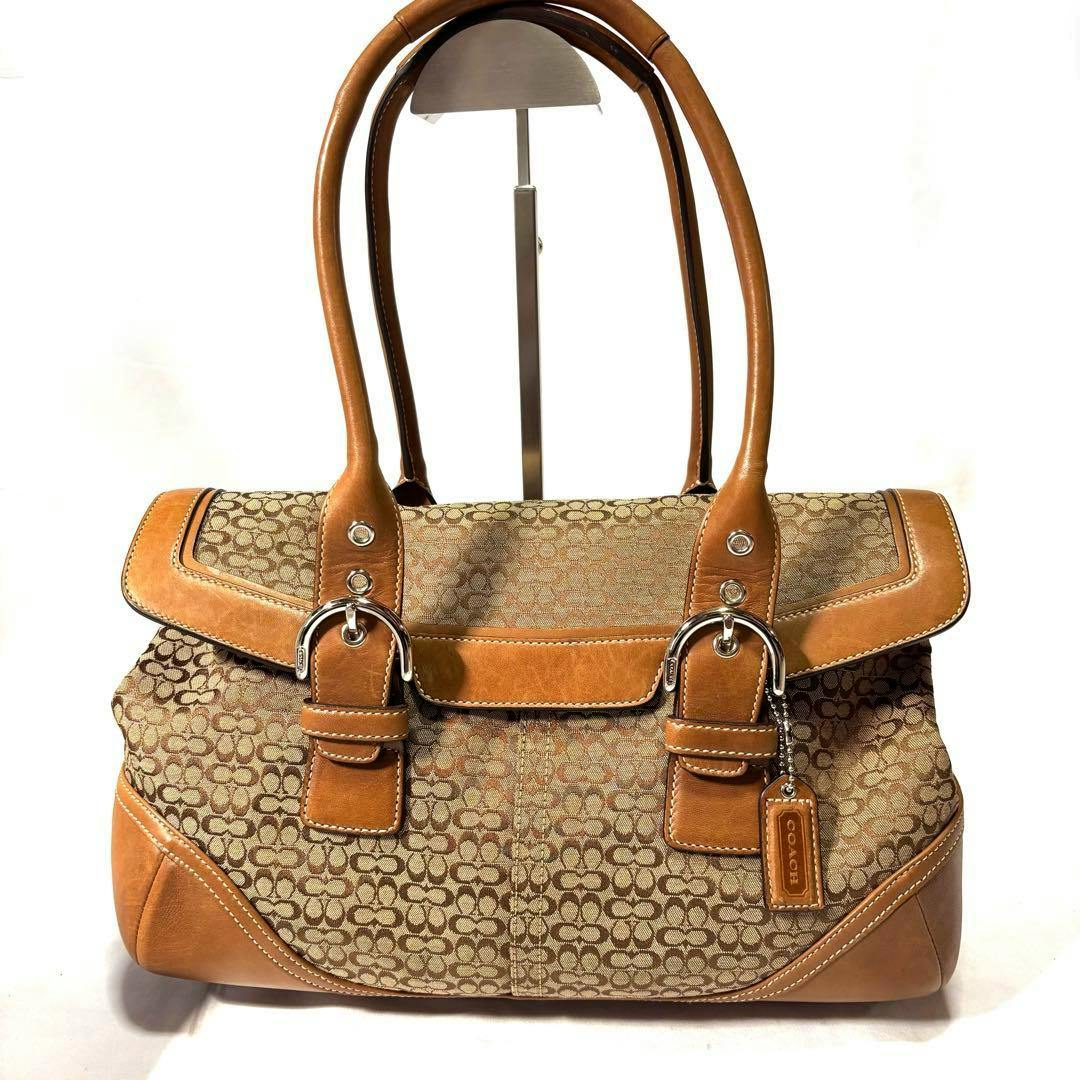 Front view of a brown COACH Soho Signature tote shoulder bag in signature canvas with tan leather trim and dual handles.