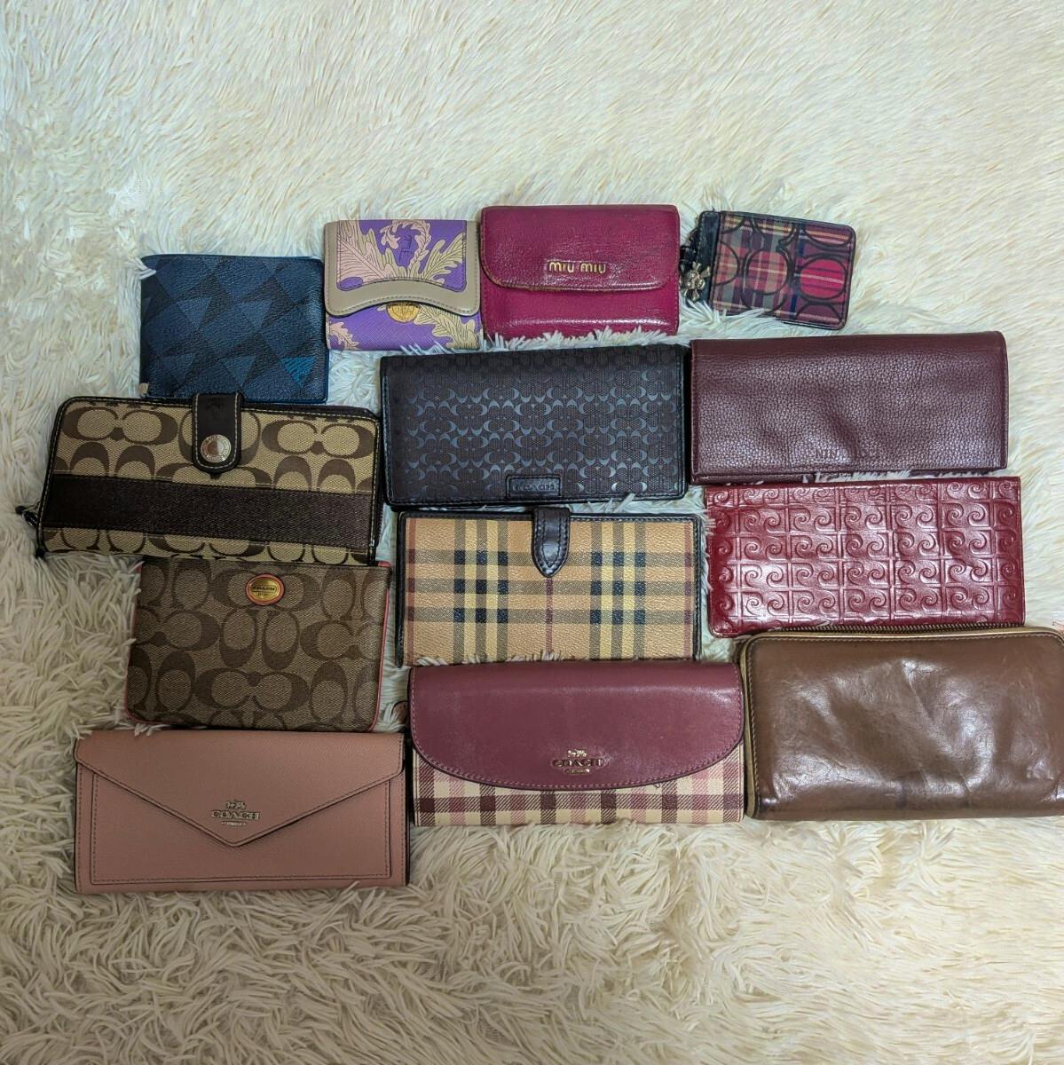 Thirteen assorted wallets and small leather goods laid out on a light-colored shag rug.