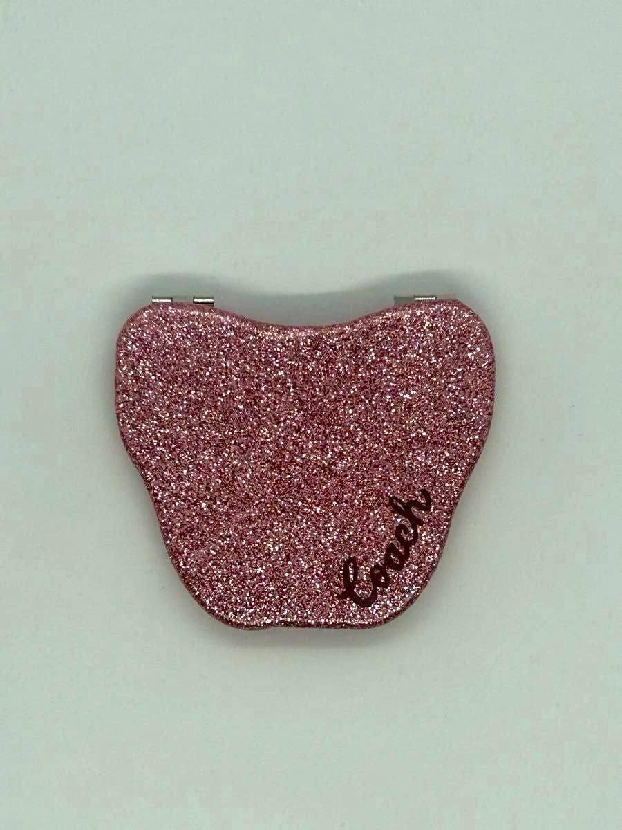Pink glitter butterfly-shaped compact mirror with a visible Coach logo on the front.