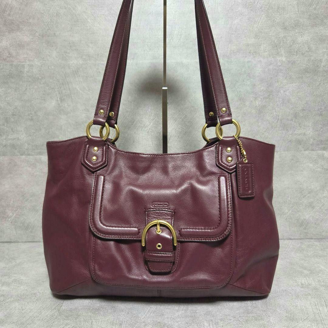 Front view of a burgundy Coach Campbell Belle Carryall cow leather tote bag with gold-tone buckle and double shoulder straps.