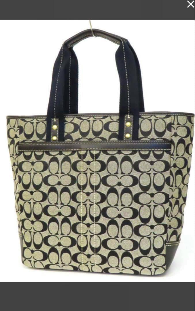 Front view of a Coach canvas tote bag with signature 'C' pattern and black handles.