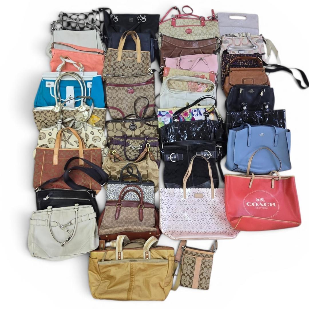 Overhead view of a large assortment of Coach bags arranged together for a bulk resale lot.
