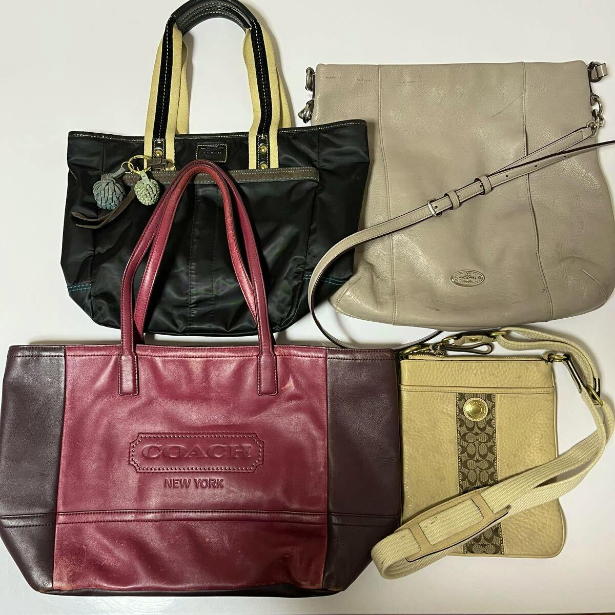 Four COACH bags (handbag, shoulder bag, tote, crossbody) arranged on a white background.