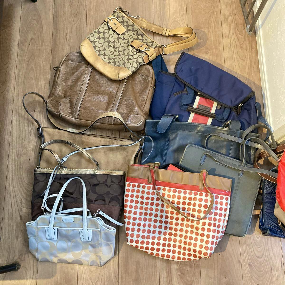 Top-down photo of nine assorted COACH bags and totes arranged on a wooden floor.