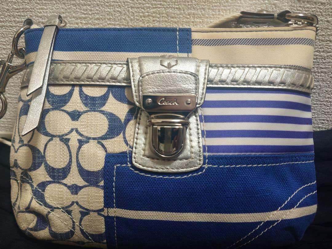 Front of a Coach canvas shoulder bag with blue-and-white patchwork pattern and a silver clasp.