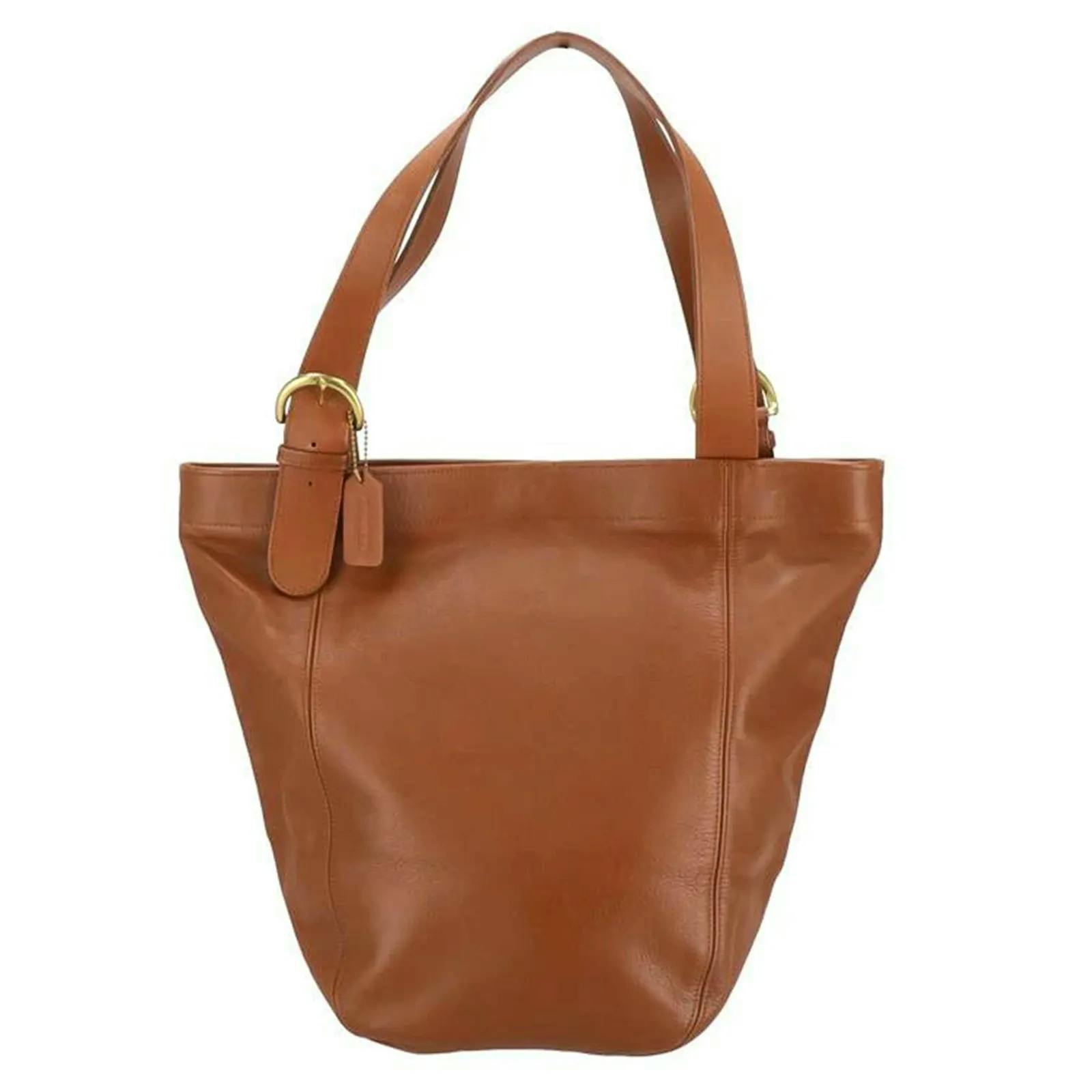 Front view of a brown COACH tote bag with shoulder straps and a hanging tag.
