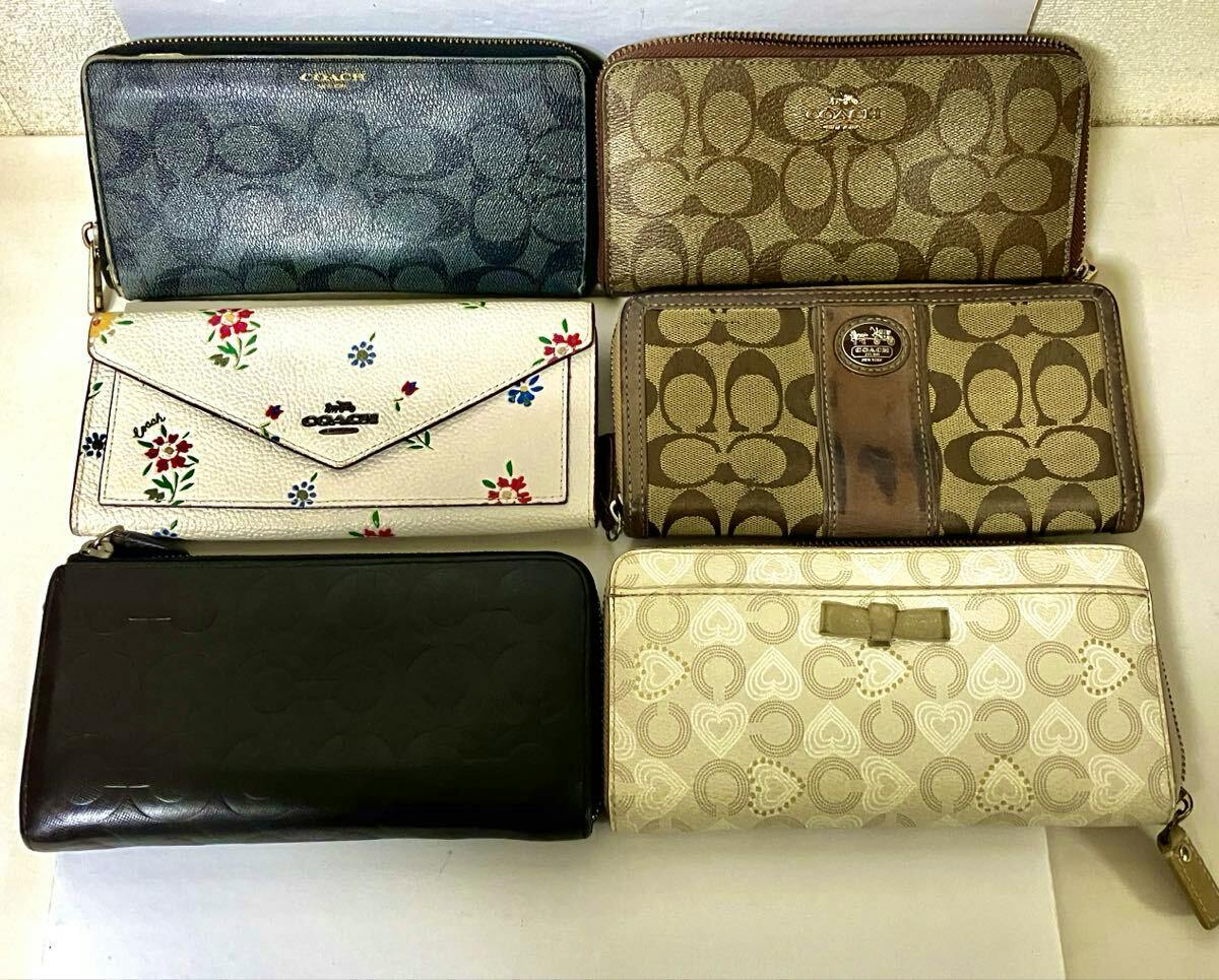 Six COACH wallets of various colors and patterns arranged on a white surface.