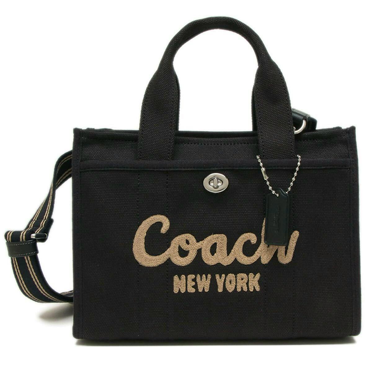 Front view of a black Coach cargo tote bag with top handles, a striped shoulder strap, and "Coach New York" embroidered on the front.