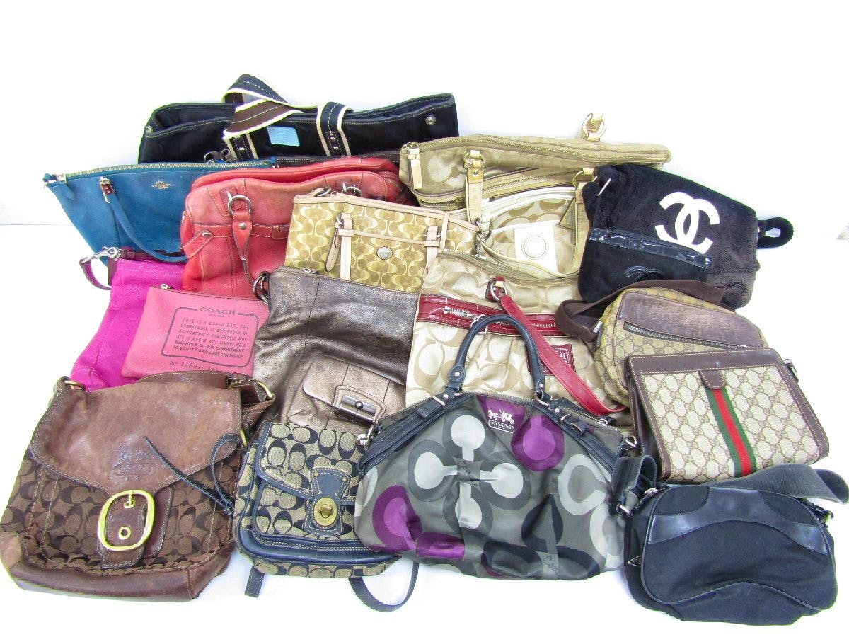A collection of assorted used designer bags (COACH, CHANEL, GUCCI, PRADA) arranged together on a white background.