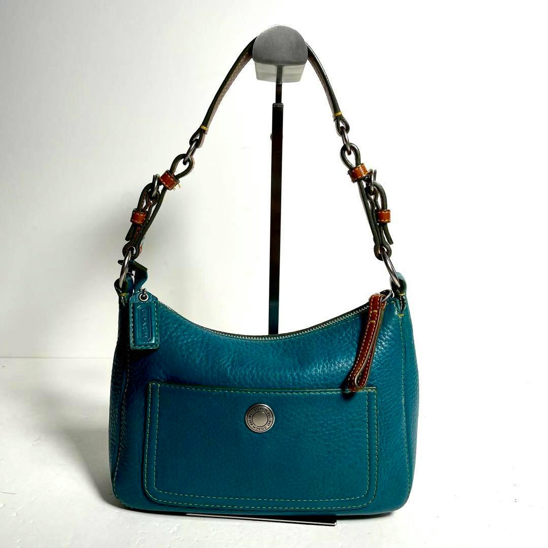 Front view of a teal pebbled leather Coach Chelsea hobo bag on a display stand.
