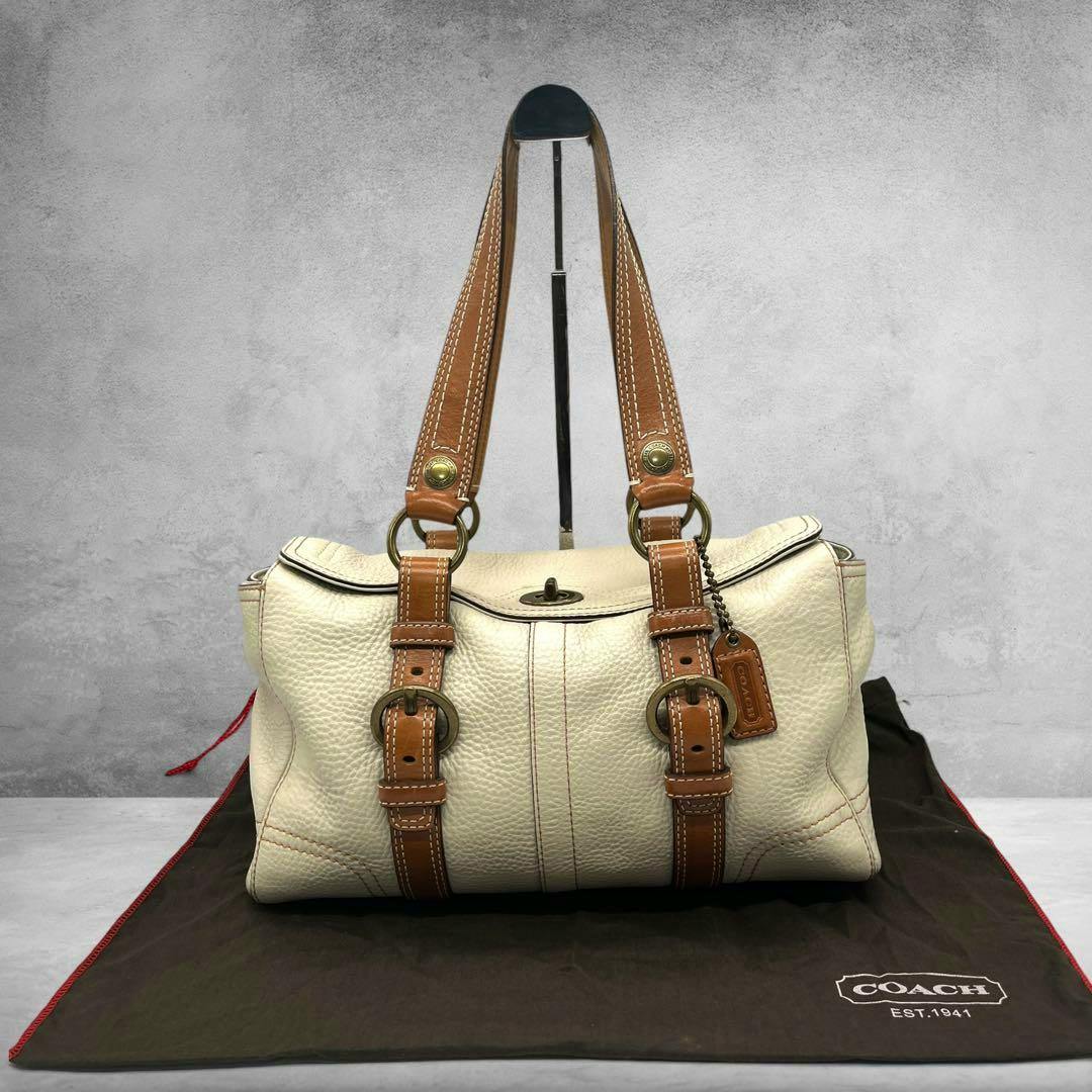 Cream COACH Chelsea leather tote with tan leather straps shown on a COACH dust bag.