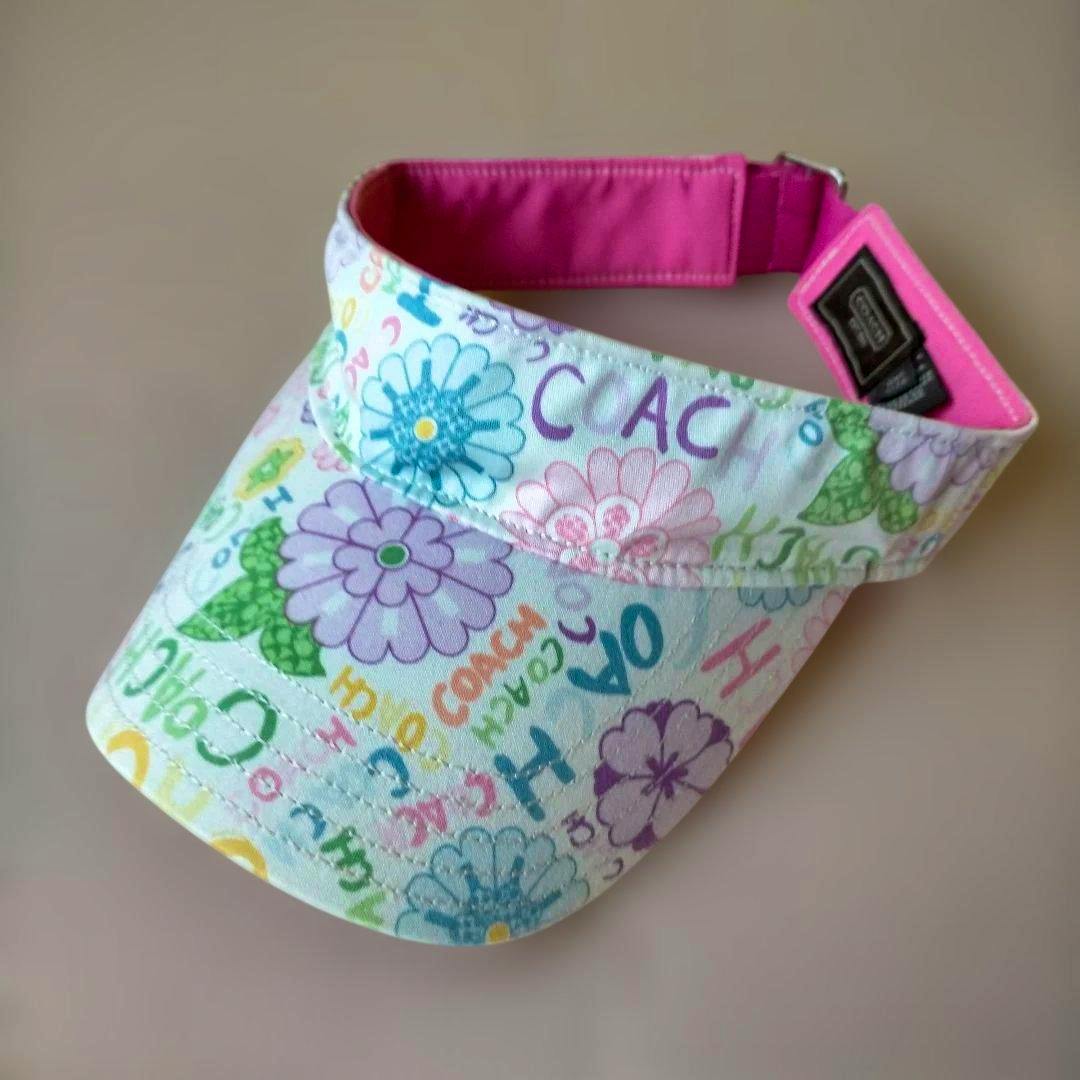 COACH floral colorful sun visor with multicolor flower print and a pink inner band.