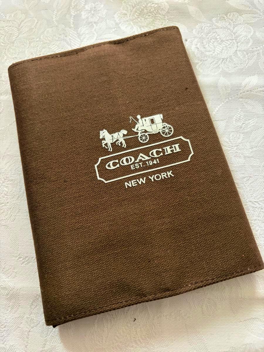 Brown COACH notebook cover showing a white coach-and-carriage logo and "NEW YORK" text.