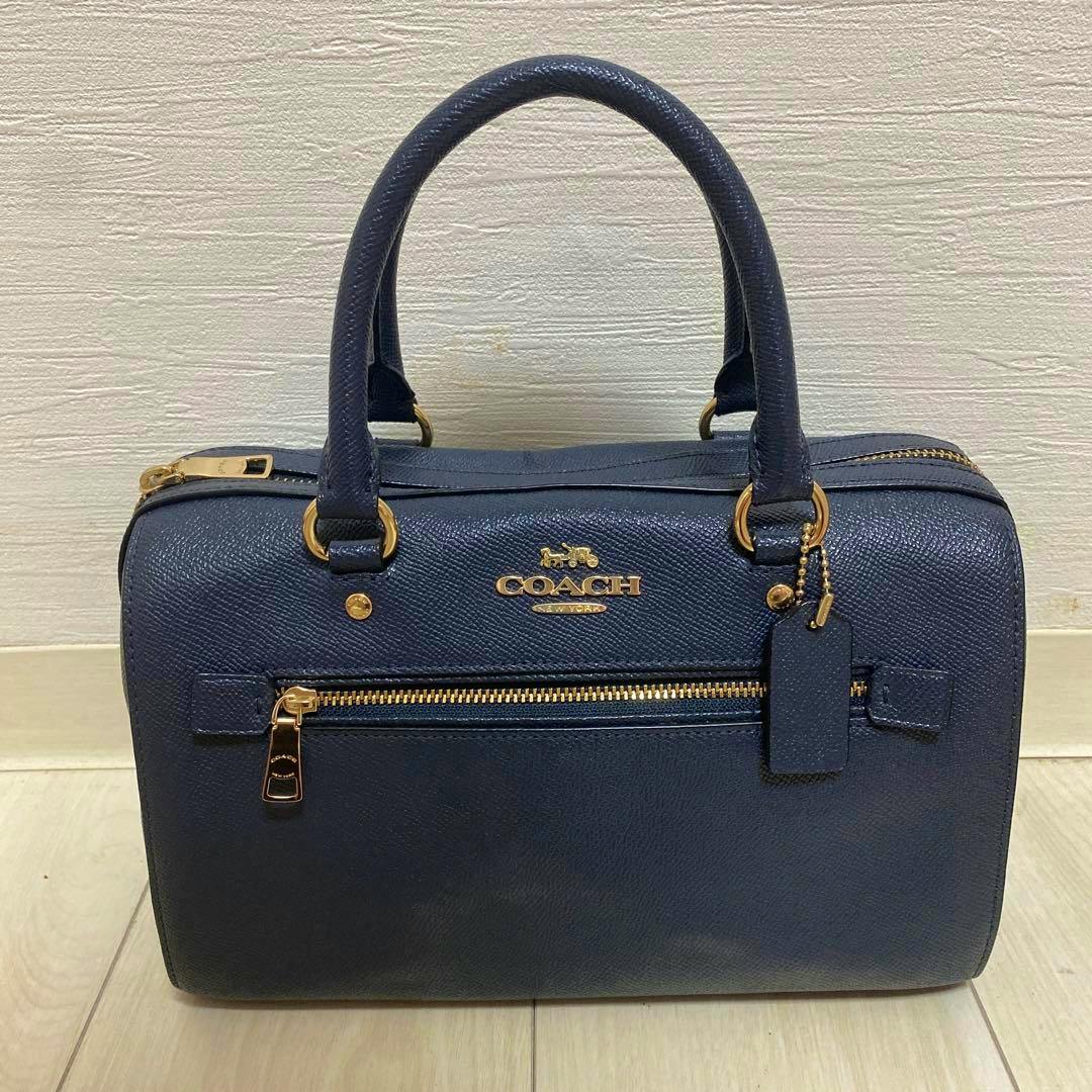 Front view of a navy Coach cow leather handbag with two top handles, a front zip pocket, and gold hardware.