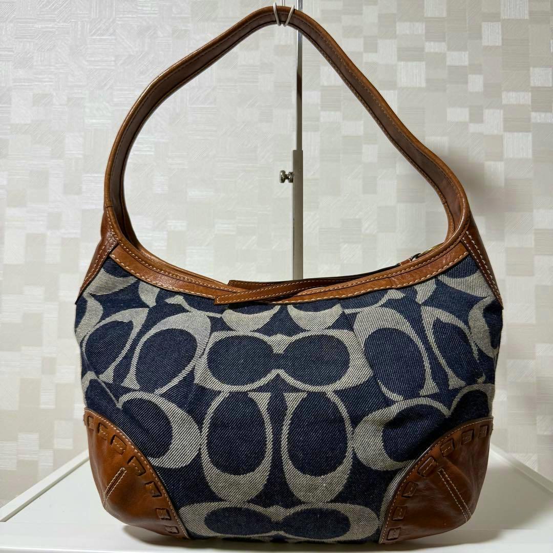 Front view of a Coach denim and brown leather hobo shoulder bag with signature C pattern.