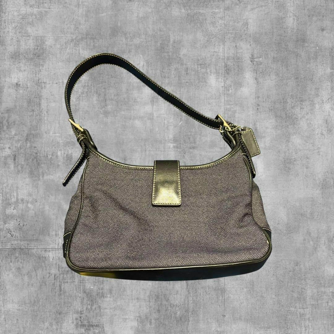 Front view of the Coach denim hobo one-shoulder bag on a gray textured background.