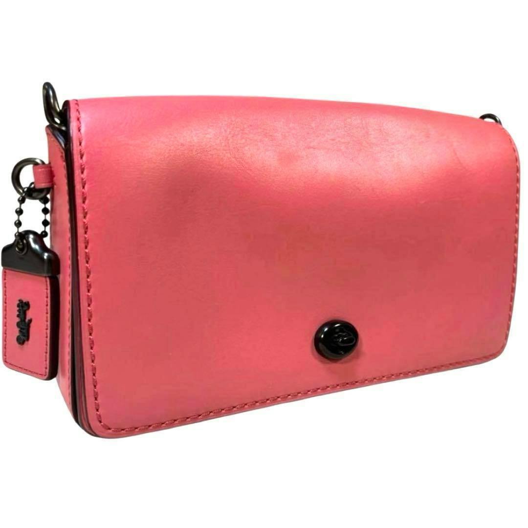 Front view of a pink leather Coach Dinky shoulder bag showing the front turnlock and side hangtag.