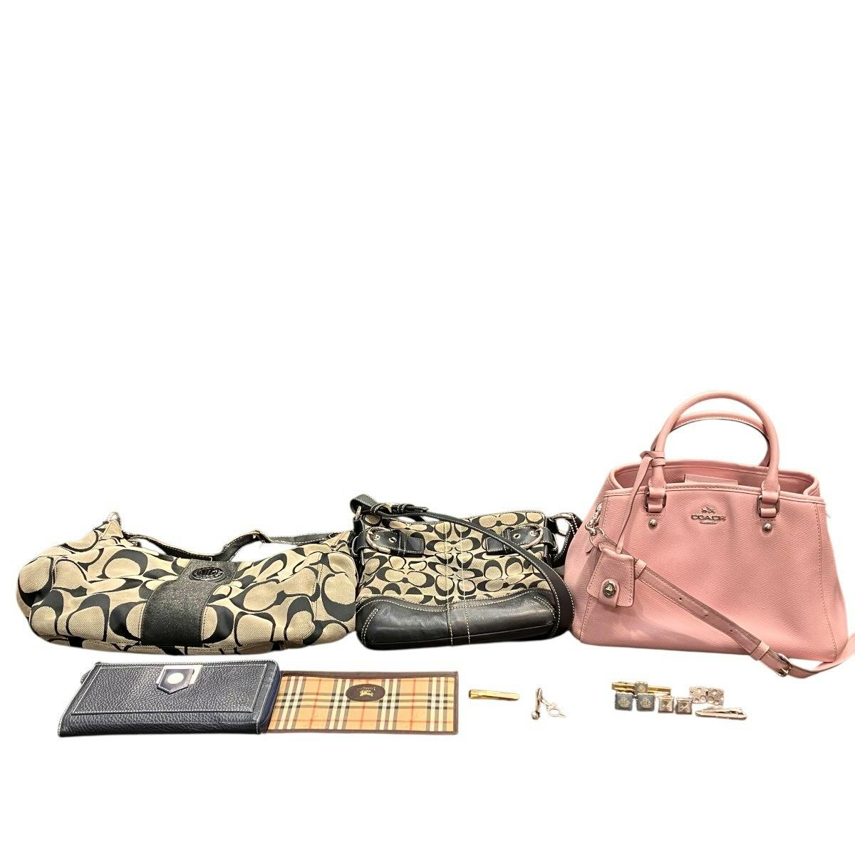 Three handbags (a pink Coach tote and two patterned shoulder bags) with wallets and small accessories laid out on a white background.