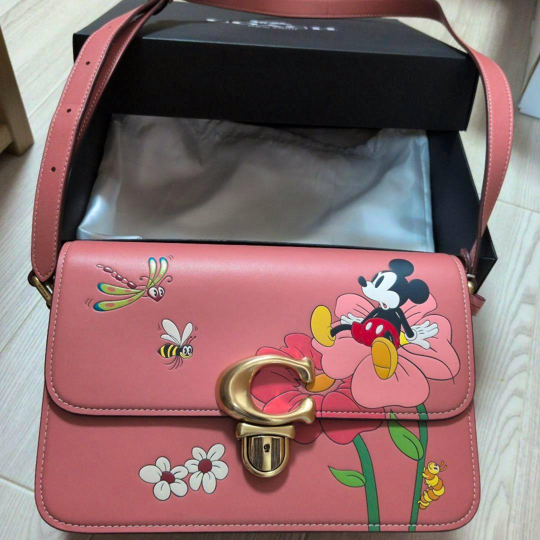 Pink Coach × Disney leather shoulder bag with a floral and Mickey Mouse print and a gold 'C' clasp, shown with its strap and box.