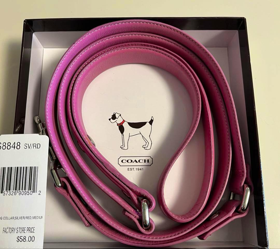 Coiled pink COACH dog leash displayed in its box with a visible price tag.