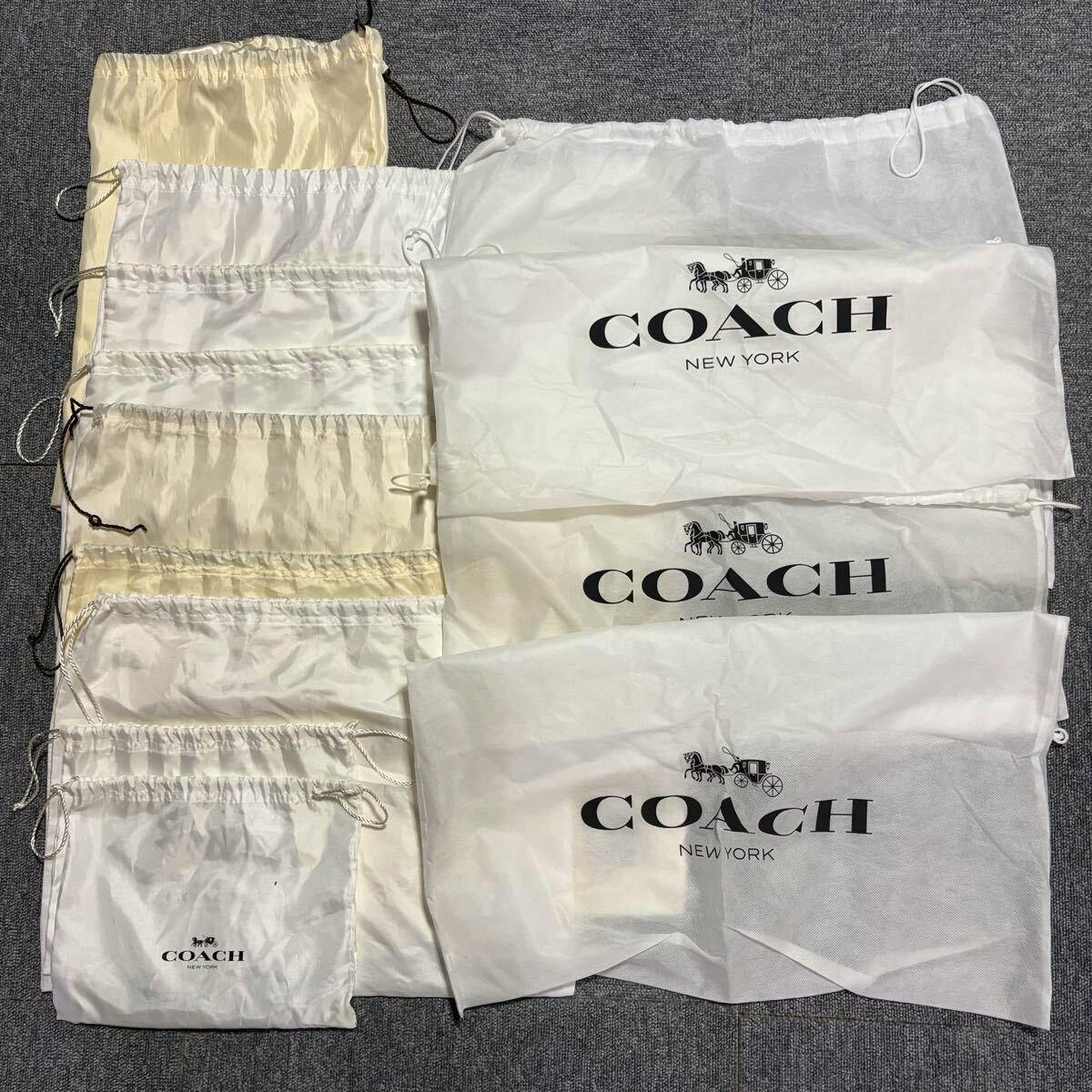 Multiple white and cream COACH drawstring dust bags laid flat showing the COACH New York logo.