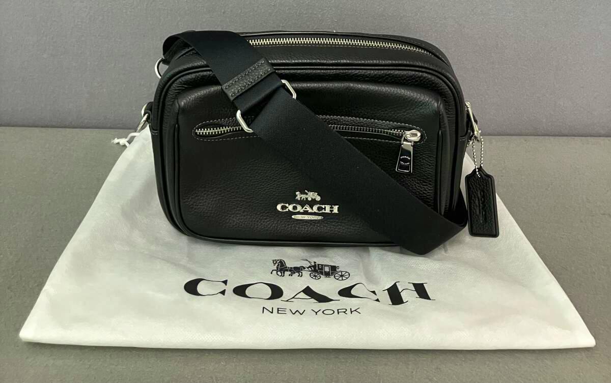 Black COACH leather crossbody shoulder bag with front zip pocket shown on a COACH dust bag.