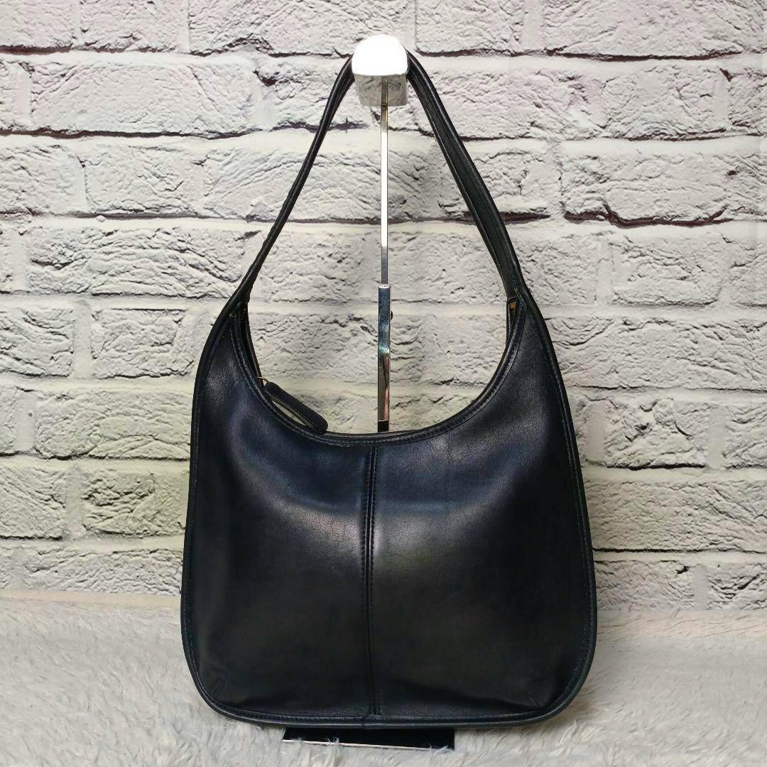 Front view of a black Coach leather one-shoulder bag displayed on a stand.