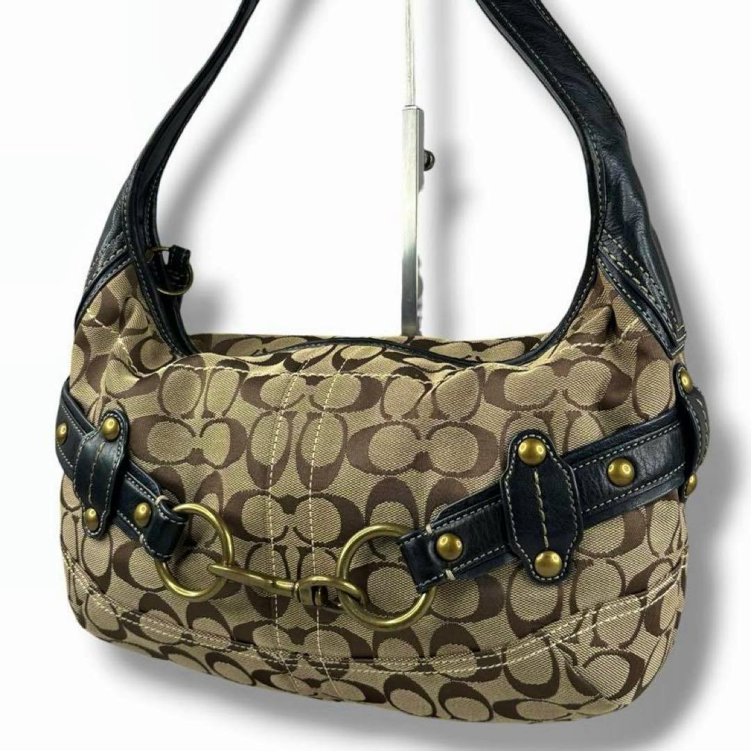Coach Ergo Hobo shoulder bag in brown signature Coach 'C' canvas with black leather trim and brass ring hardware displayed on a stand.