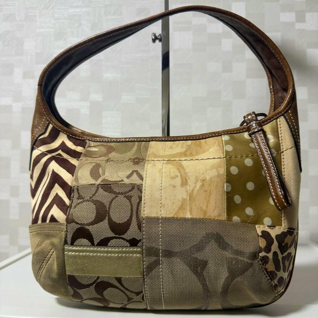 Front view of a Coach patchwork canvas and leather shoulder hobo bag with a brown leather strap.