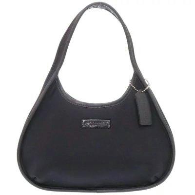 Front view of a black COACH Ergo mini canvas handbag with a single shoulder strap and a hanging leather tag.