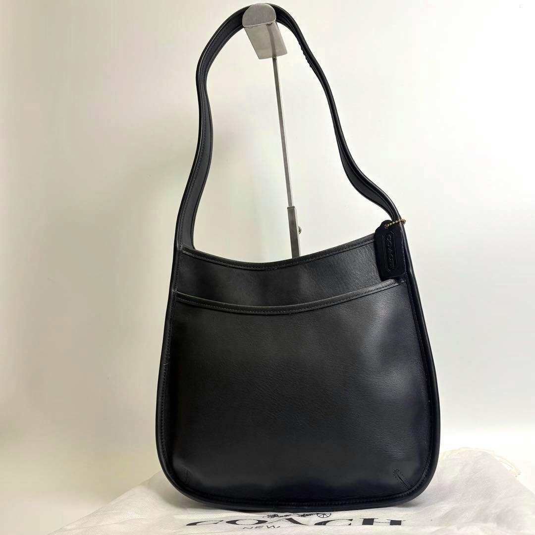 Front view of a black Coach Ergo one-shoulder cow leather bag displayed on a stand.