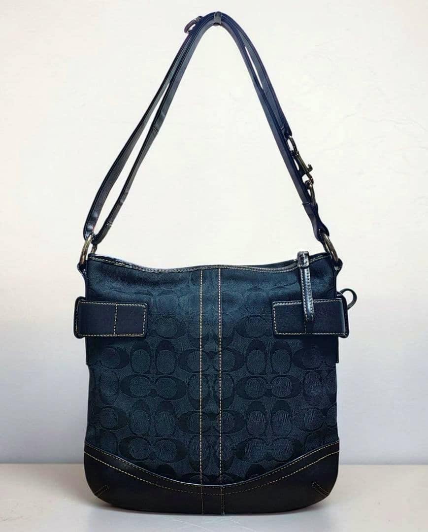 Front view of a black COACH signature canvas shoulder bag with leather trim and an adjustable shoulder strap.