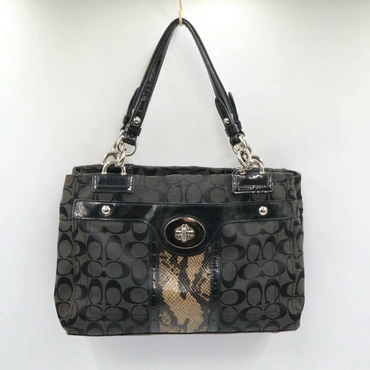 Front view of a black Coach signature canvas tote handbag with double shoulder handles and a front turn-lock pocket.