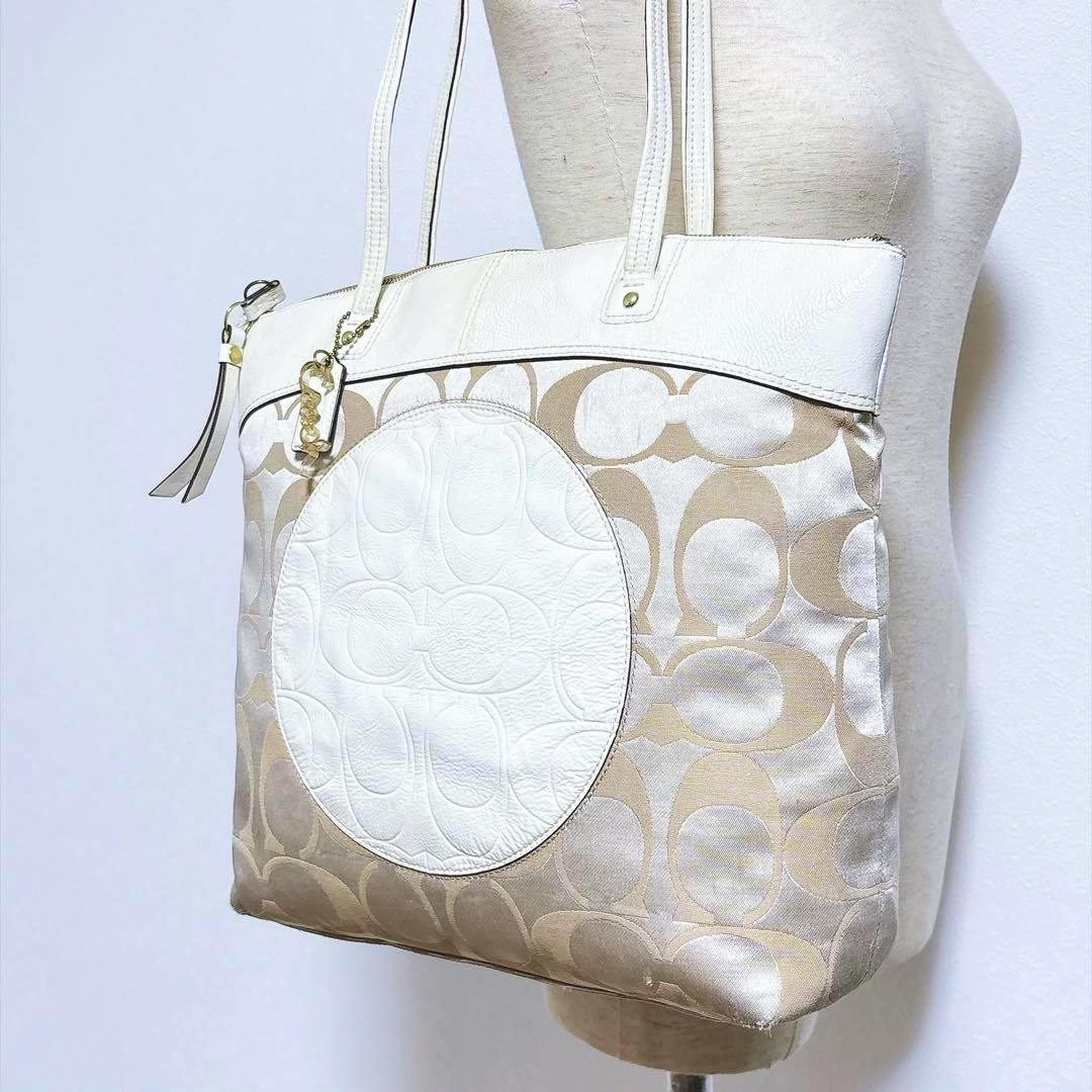 White Coach signature canvas tote bag with a large circular white leather patch shown on a dress form.