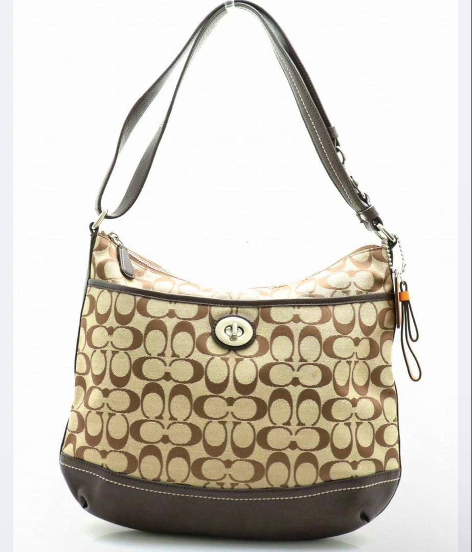 Frontal view of a Coach signature canvas shoulder hobo bag with turnlock closure and leather trim.