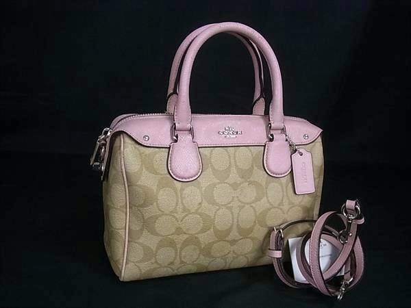 Coach signature canvas 2-way crossbody handbag in brown with pink leather trim and detachable strap on a black background.