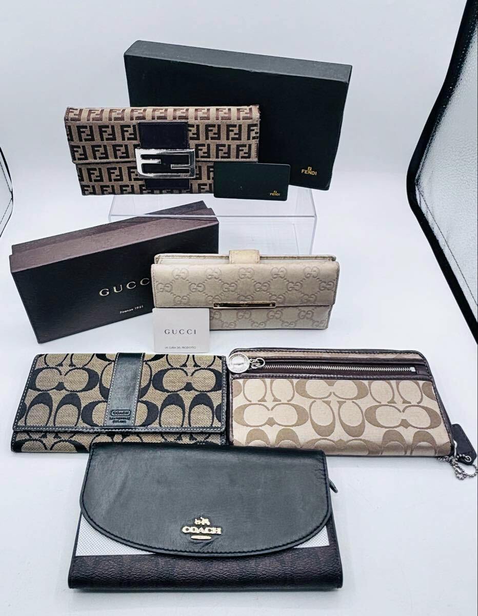 Five branded long wallets (Coach, Fendi, Gucci) with their boxes arranged on a white surface.