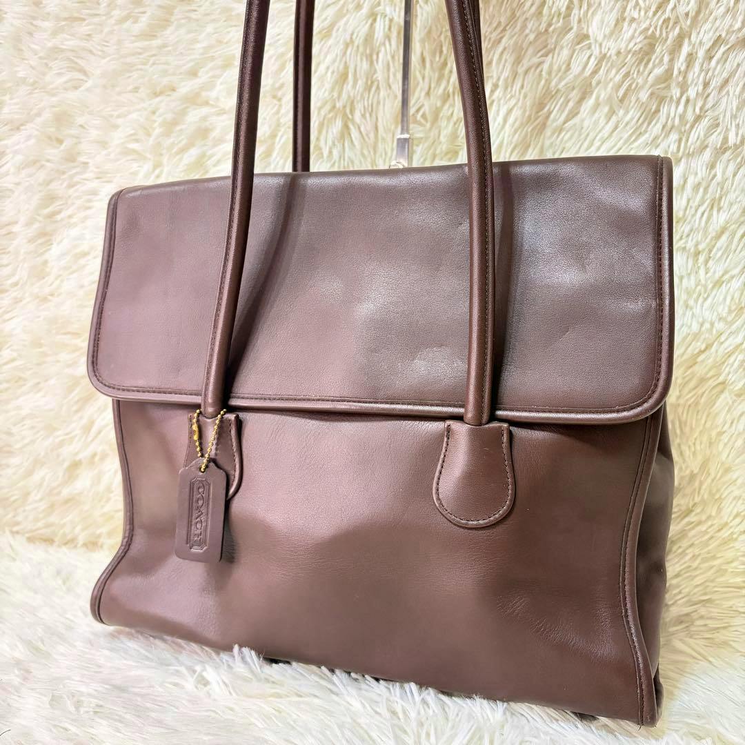 Brown COACH flap shopper grab-tan leather tote bag front view with top handles and a leather hang tag.