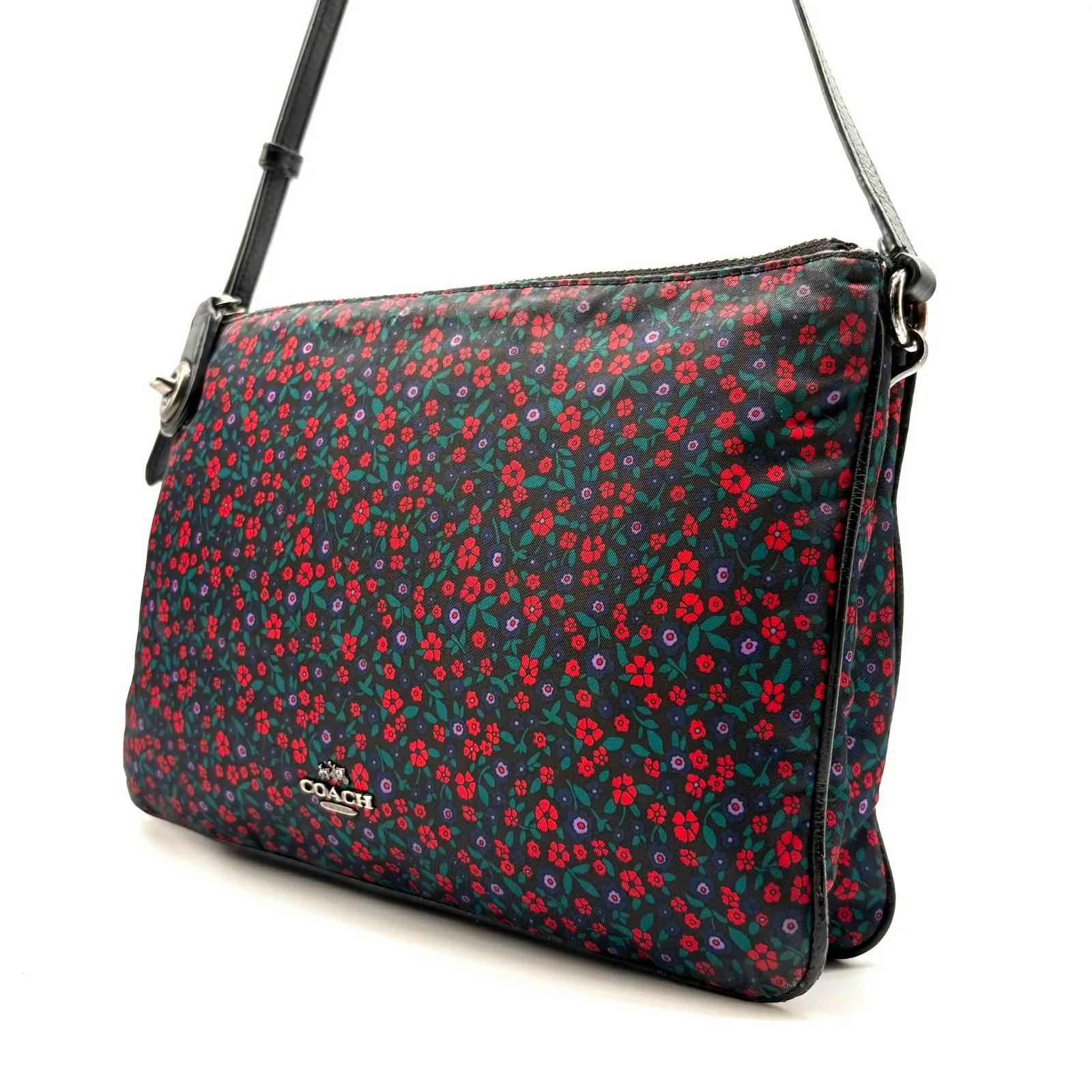 Front view of a Coach floral-print nylon crossbody shoulder bag showing the front panel, leather strap, and metal Coach logo.