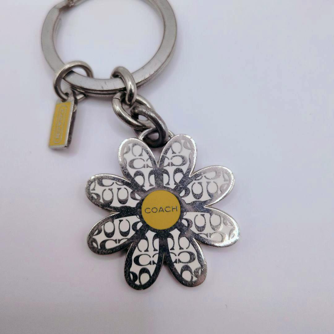 COACH silver flower bag charm with a yellow center attached to a key ring.