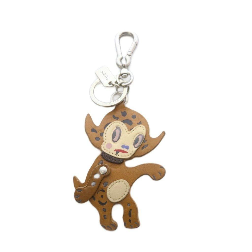 Brown leather COACH × Gary Baseman character keychain with metal clasp, key ring, and small logo tag.