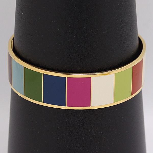 Gold-tone Coach bangle bracelet with multicolor enamel rectangular panels displayed on a black cone.