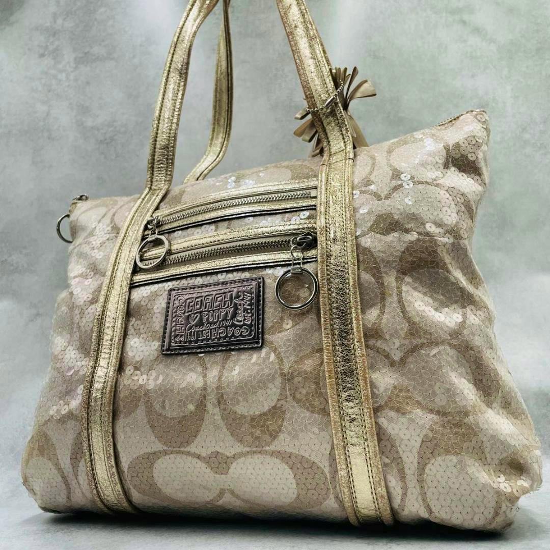 Coach gold canvas tote bag (nylon) with sequins, dual top handles, front zip pockets, and a Coach logo patch.