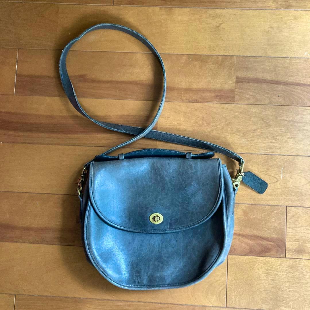 Gray leather COACH shoulder bag lying flat showing the front flap, turn-lock, and strap.