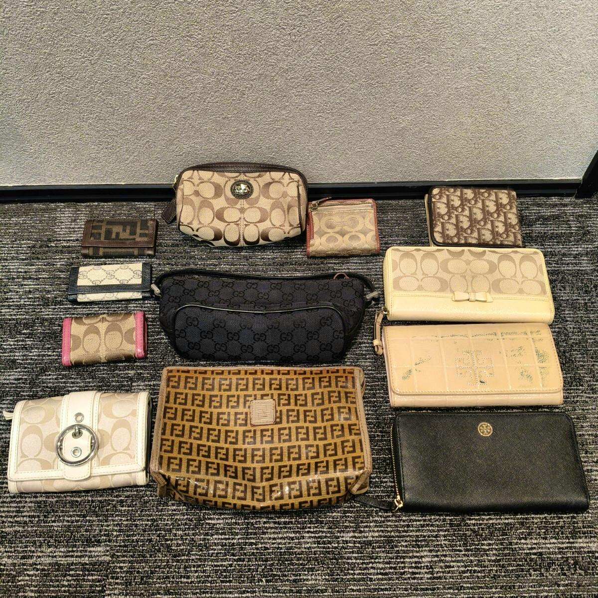A set of Coach, Gucci, Fendi, and Dior wallets and pouches arranged on a carpeted floor.