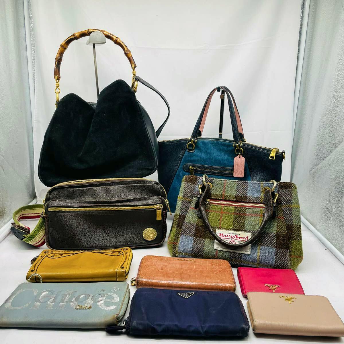 A group of handbags and wallets arranged on a white background, showing several shoulder bags and assorted wallets.