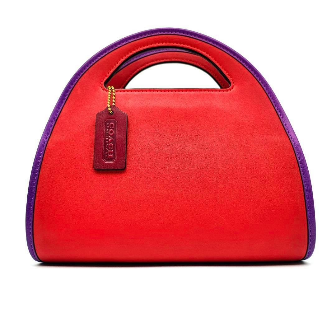 Front view of a COACH half-moon zip-dome crossbody bag in red leather with purple trim and a COACH hang tag.