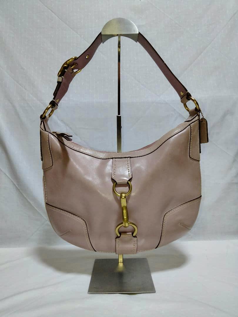 Front view of a light pink Coach leather Hamptons hobo shoulder bag with brass ring hardware on a display stand.