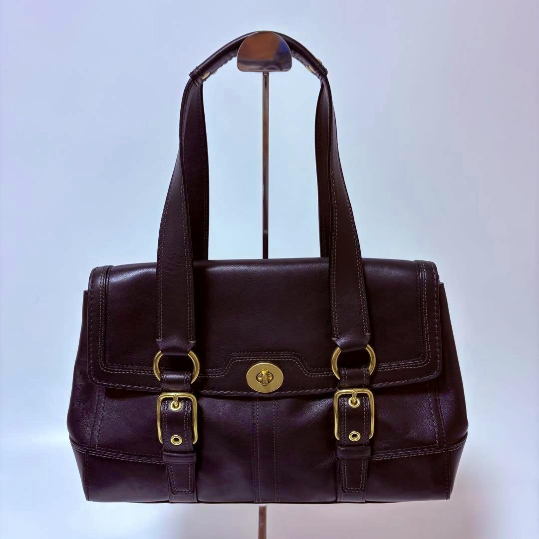 Front view of a black COACH Hamptons leather tote bag with turnlock closure and double shoulder straps.