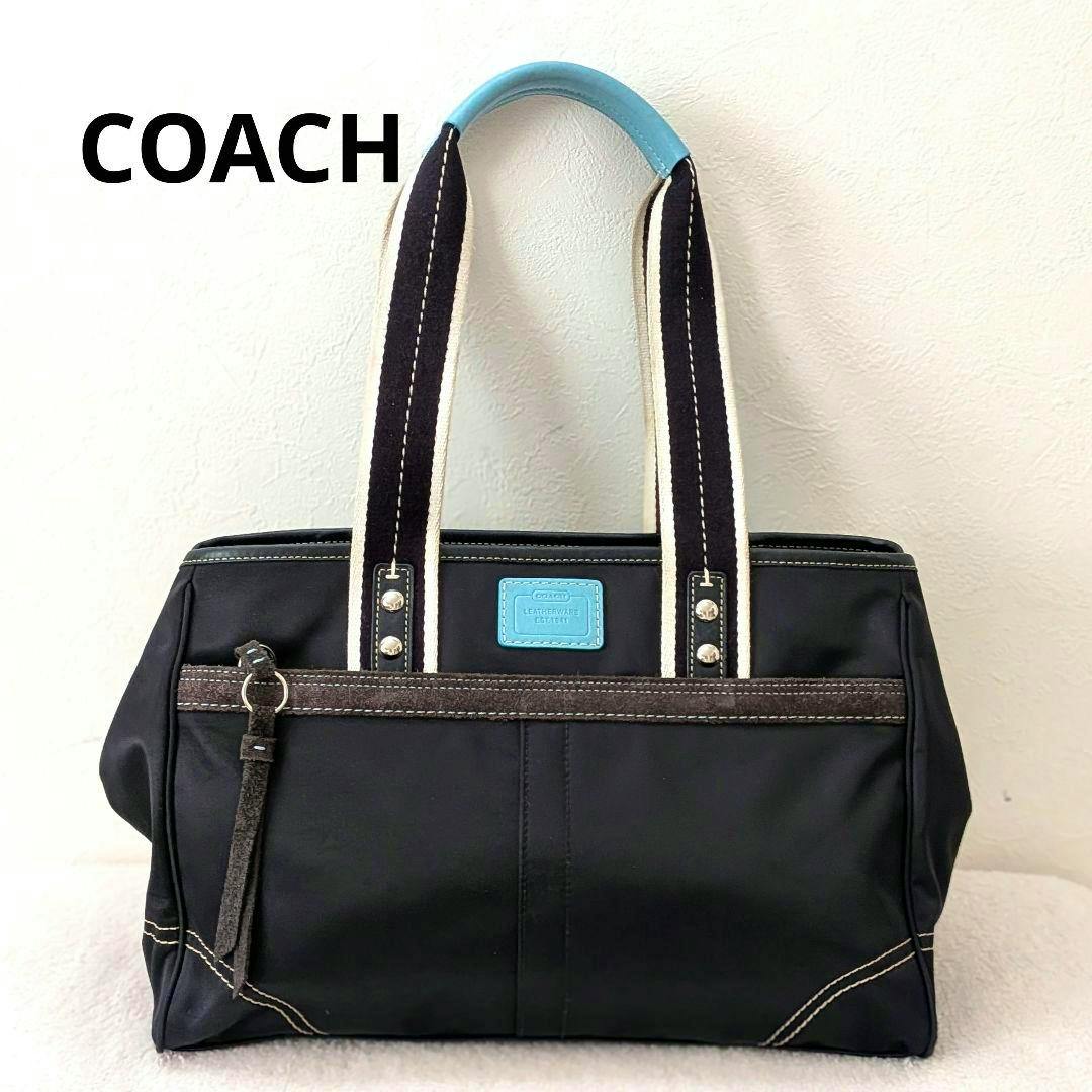 Front view of the COACH black and light-blue nylon tote bag showing handles, front pocket, and logo patch.